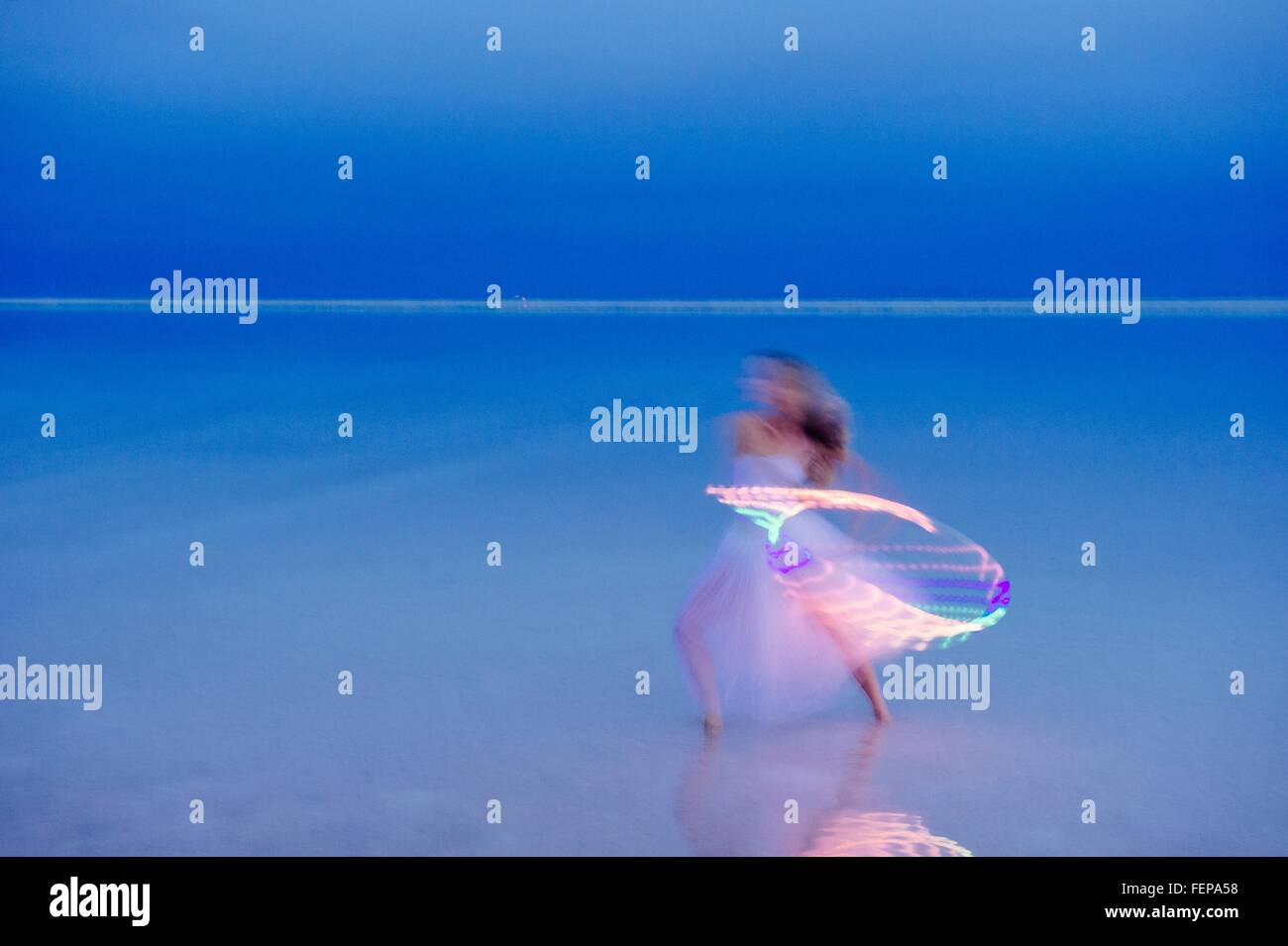 Woman wearing party dress prête avec cerceau illuminé au crépuscule Banque D'Images