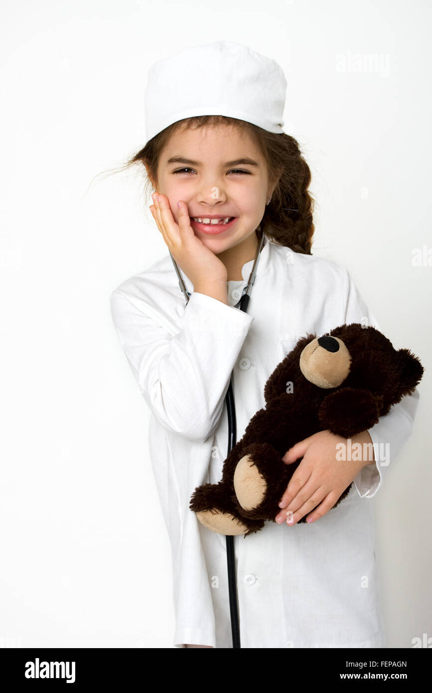 Petite fille médecin dans l'uniforme blanc avec stéthoscope et ours malade Banque D'Images