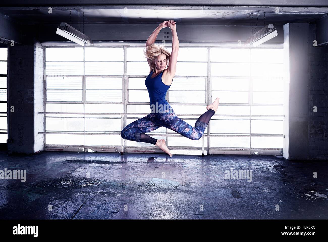 Danseuse en sautant en face de la fenêtre de l'entrepôt Banque D'Images