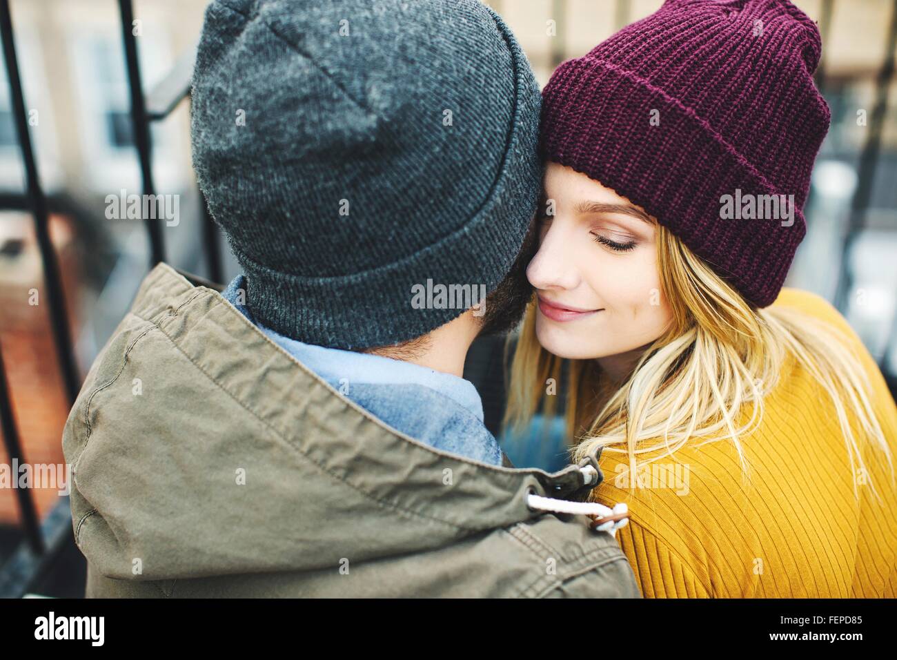 Couple portant des chapeaux tricotés sitting on stairway Banque D'Images