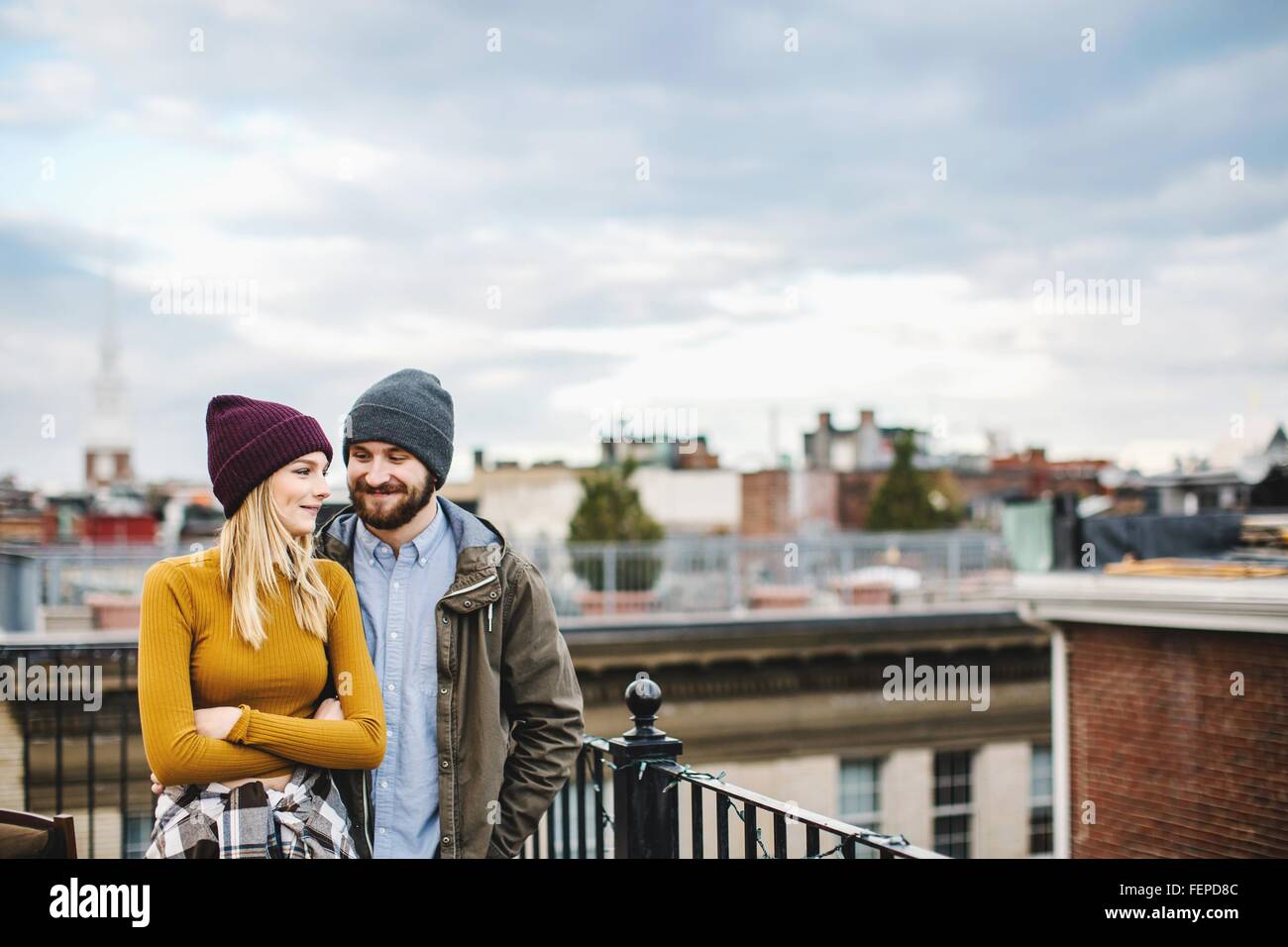 Jeune couple debout sur le toit-terrasse de la ville Banque D'Images