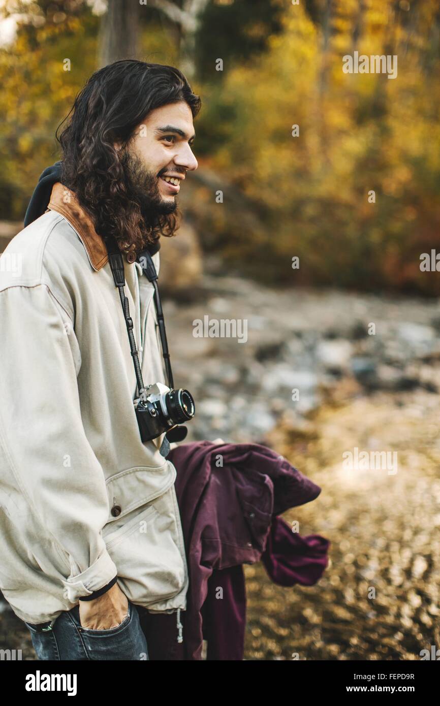 Jeune homme, en milieu rural, l'appareil photo autour du cou, smiling Banque D'Images