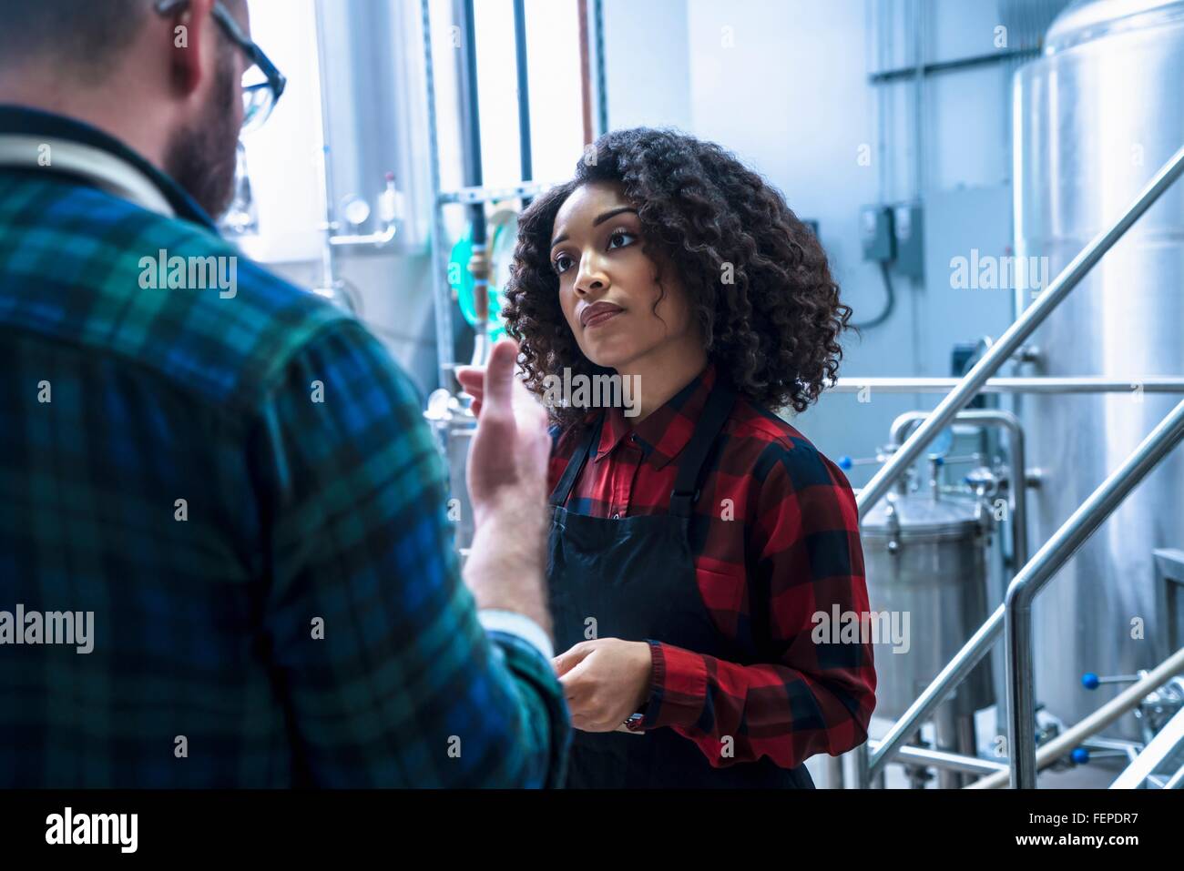 Mid adult woman in brewery écoute de collègue Banque D'Images