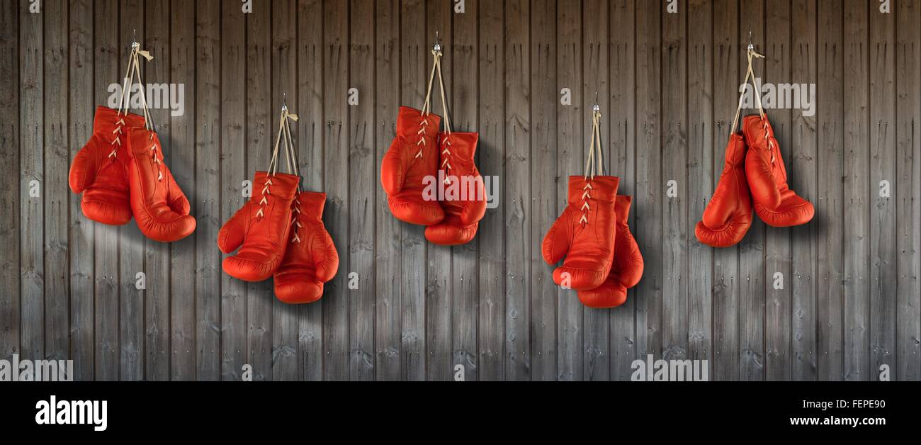 Rangée de gants de boxe rouge accrochée à un mur lambrissé de bois Banque D'Images