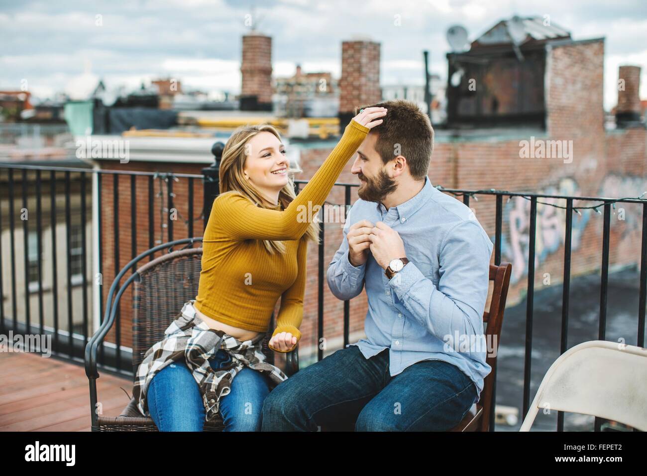 Happy young couple sitting on city Rooftop Terrace Banque D'Images
