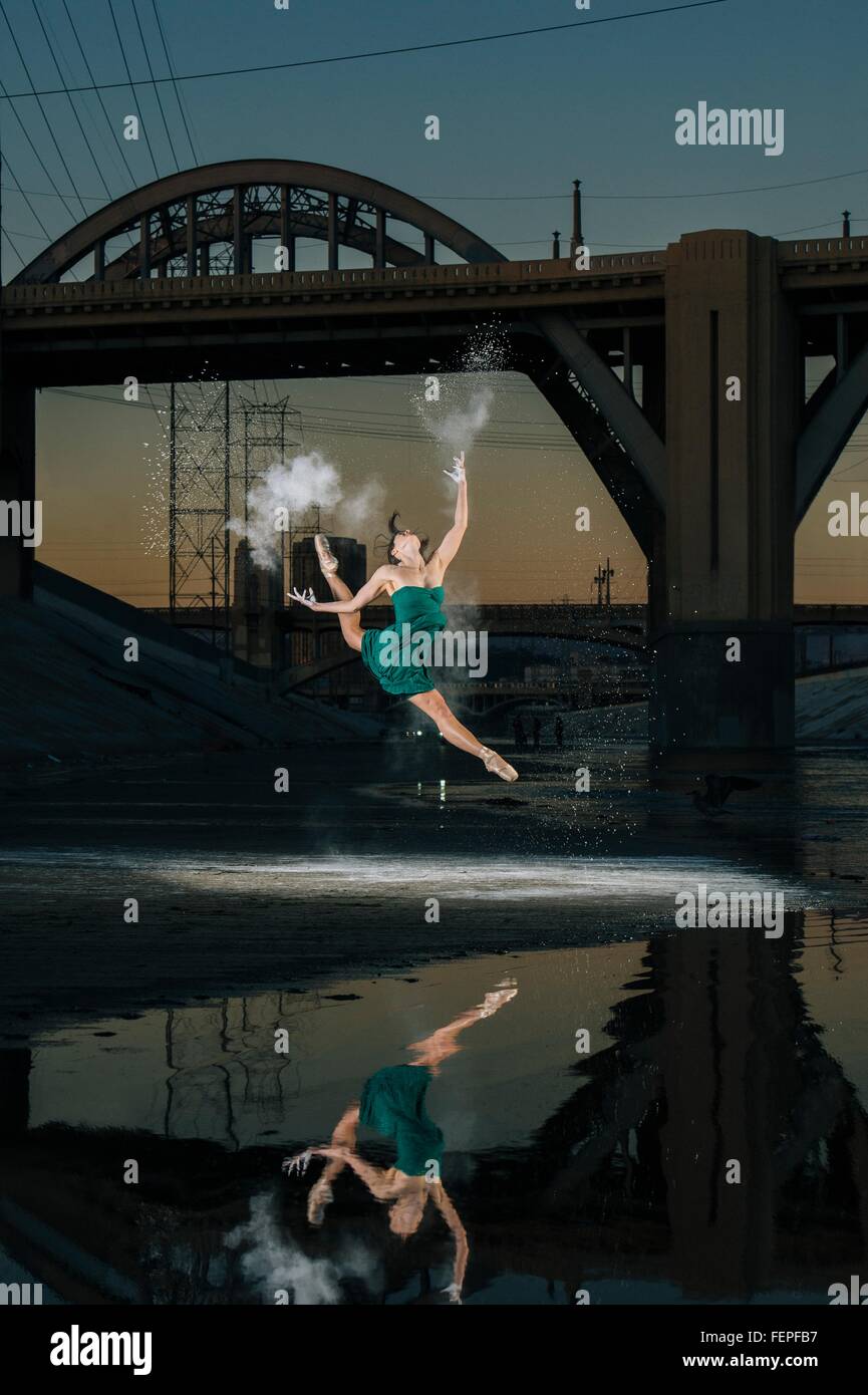 Ballerine femme sautant tout en relâchant explosion au-dessus de poudre river au coucher du soleil, Los Angeles, USA Banque D'Images