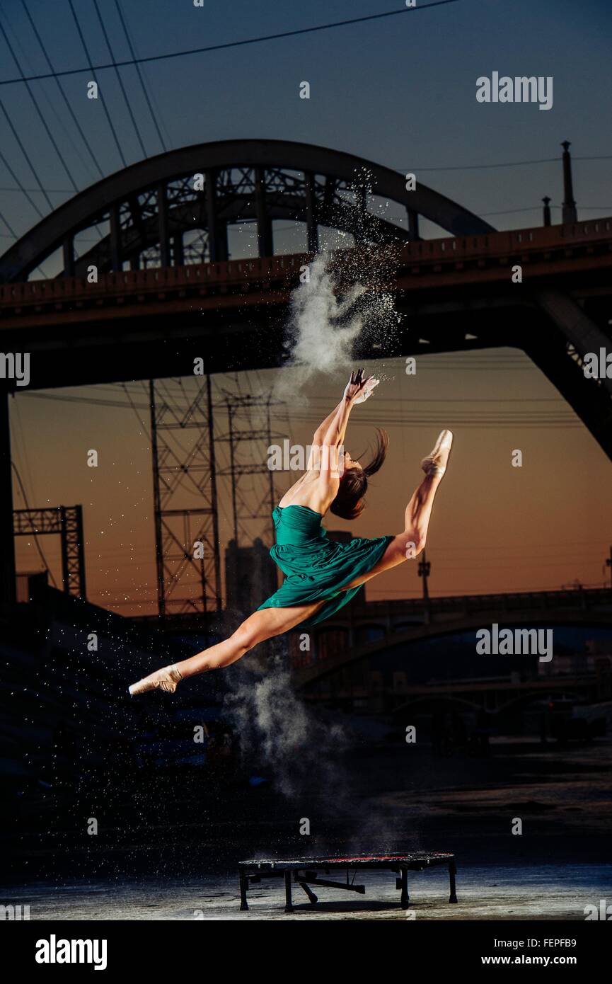 Danseuse en sautant tout en relâchant l'explosion de poudre au coucher du soleil, Los Angeles, USA Banque D'Images