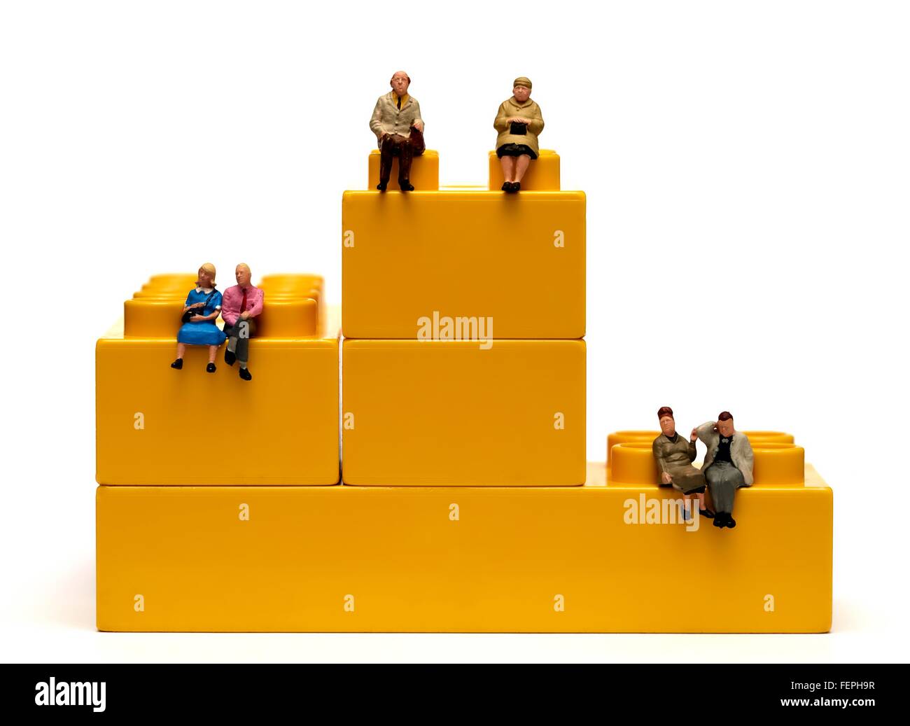 3 figurine miniature des couples assis sur des briques en plastique jaune d'enclenchement 1er 2e troisième concept pension Banque D'Images
