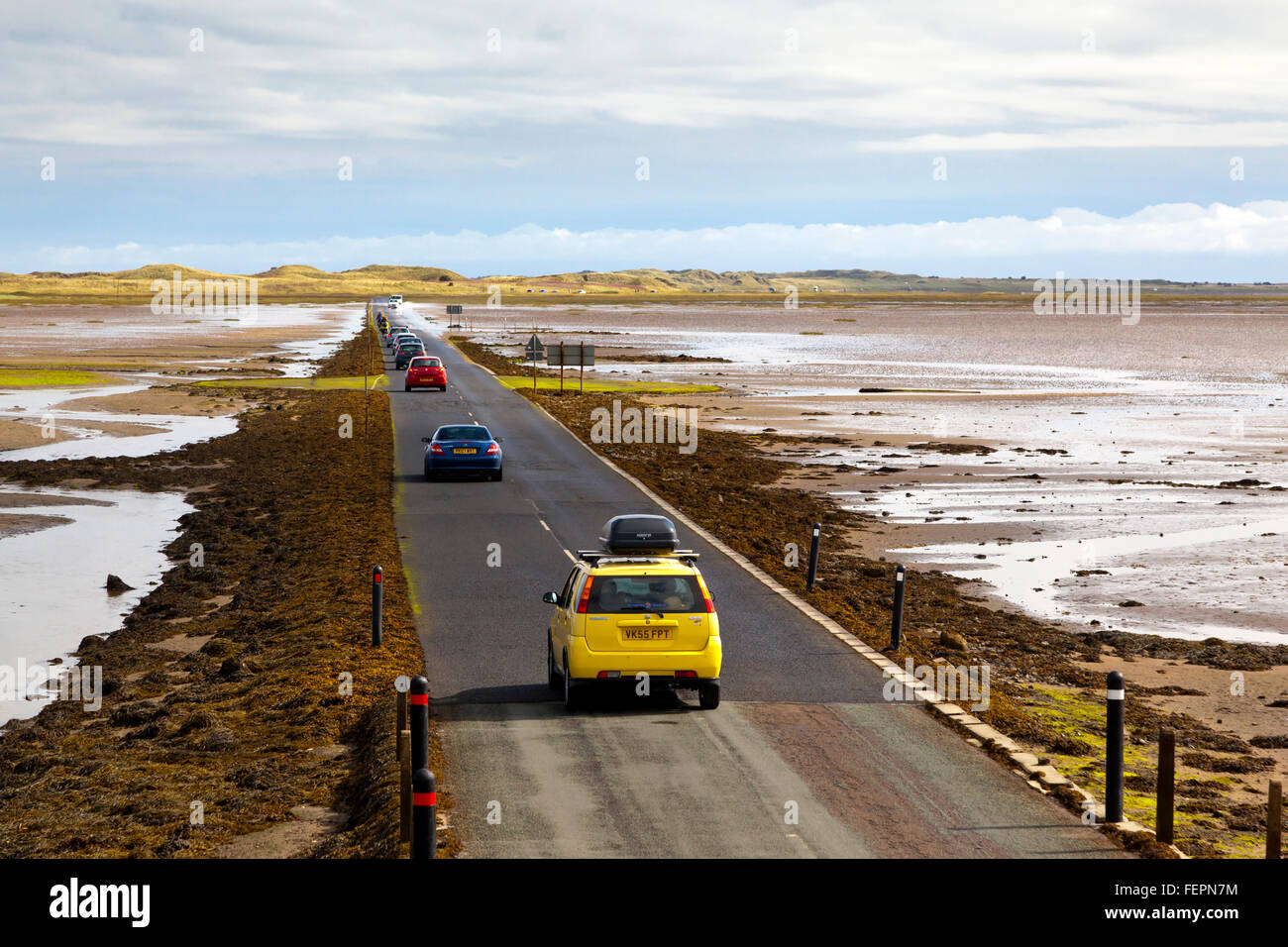 Les voitures sur la chaussée menant à l'île de Lindisfarne ou saint dans le Northumberland England UK qui est coupé par la mer deux fois par jour Banque D'Images