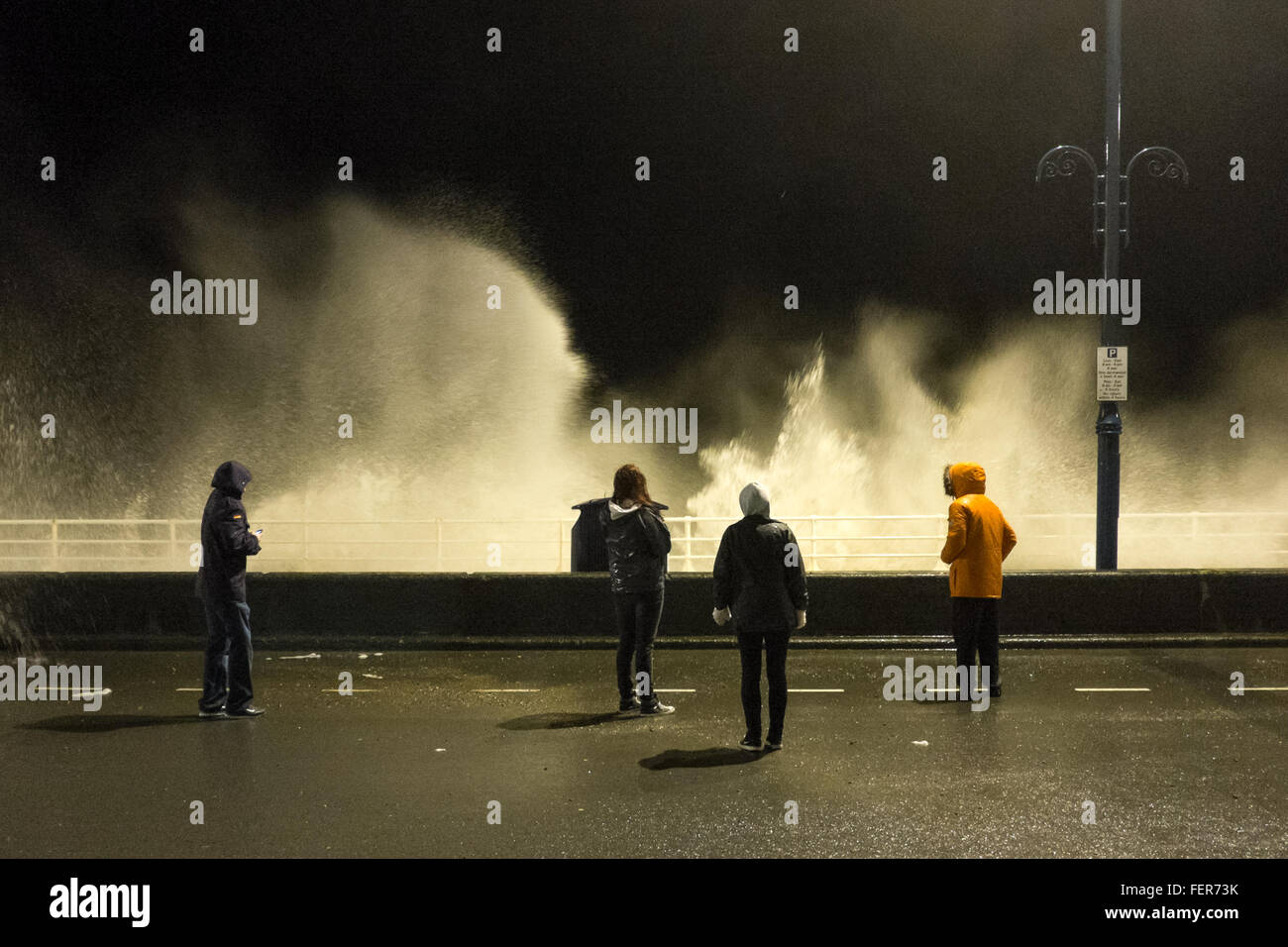 Aberystwyth, Pays de Galles, Royaume-Uni. 8 février 2016. Comme les grands vents et des vagues énormes portées par la tempête Imogen continuent à batter Aberystwyth, promenade de nuit, jeunes gens dodge les vagues Crédit : Alan Hale/Alamy Live News Banque D'Images