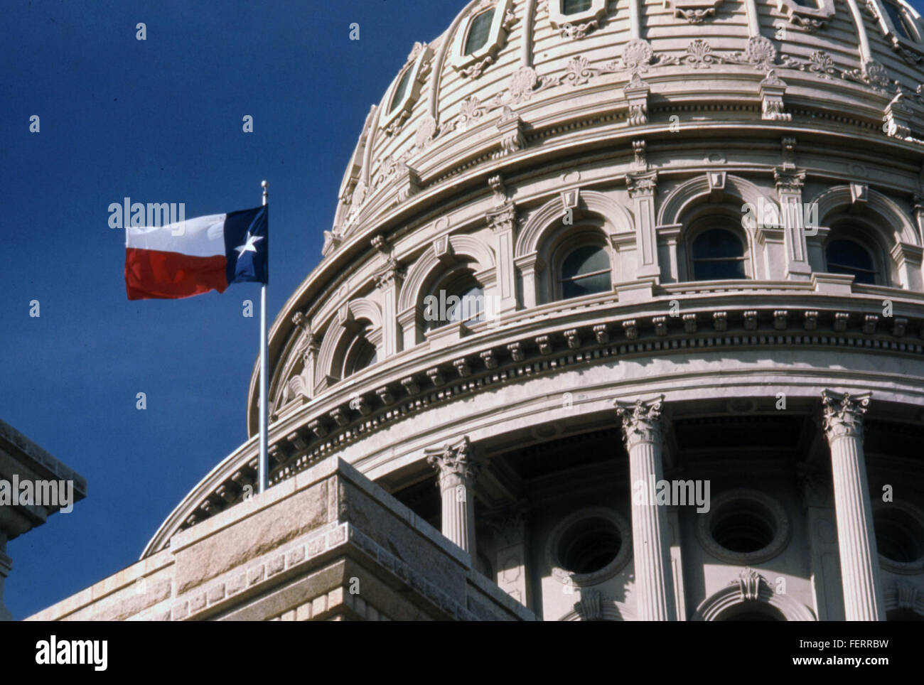 Une photographie du bâtiment du Capitole de l'État du Texas à Austin, avec le drapeau de l'État du Texas flottant bien en vue. L'image souligne l'étoile solitaire, symbolisant l'identité et la fierté du Texas en tant qu'État indépendant. Banque D'Images