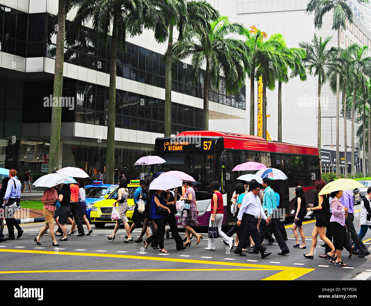 Les personnes qui traversent la rue sous la pluie à Singapour Centre-ville. Banque D'Images