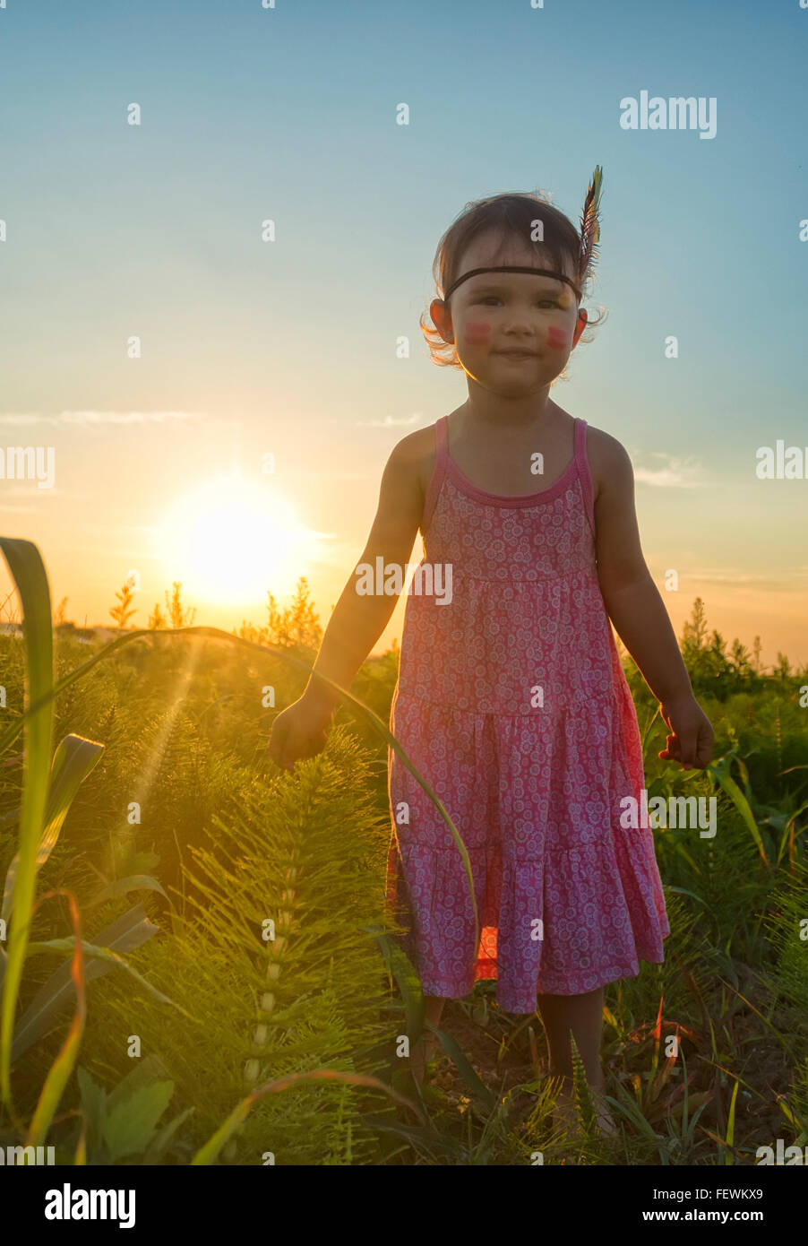 Funny little girl comme indien avec plumes et maracas Banque D'Images