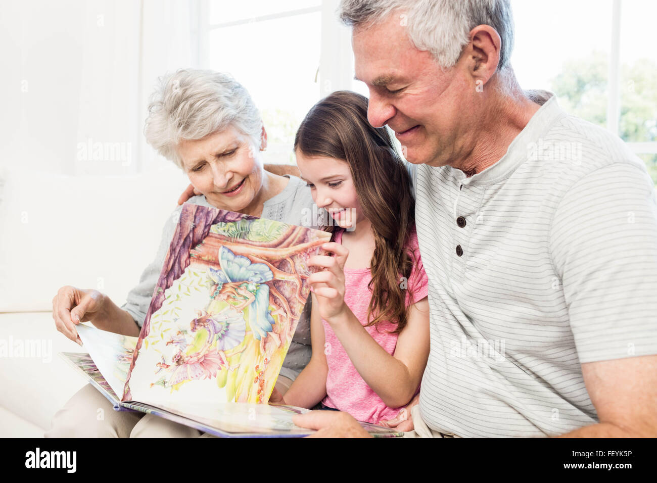 Les grands-parents heureux avec sa petite-fille lire un livre Banque D'Images