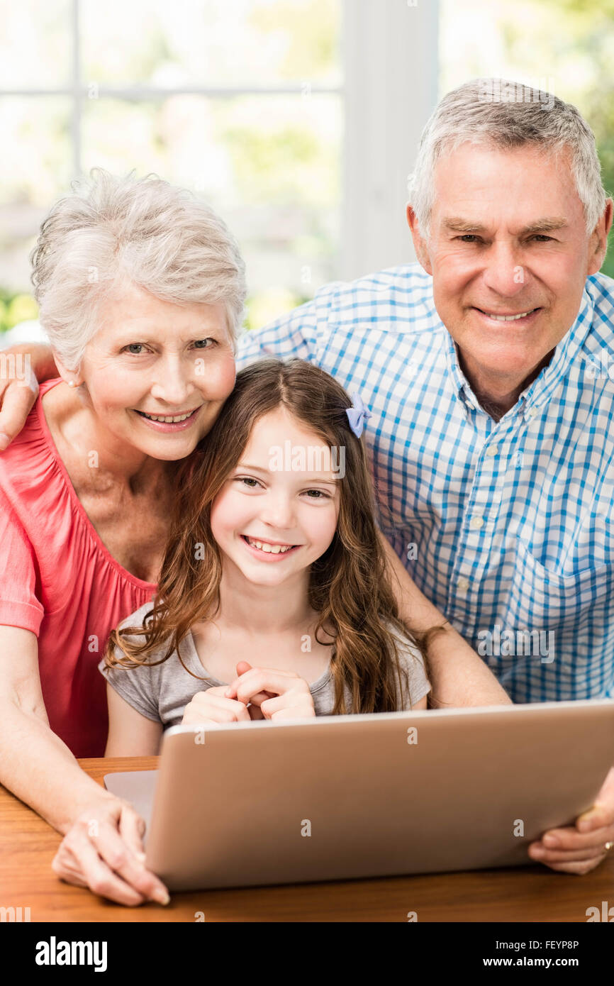 Portrait of smiling grandparents and granddaughter using laptop Banque D'Images