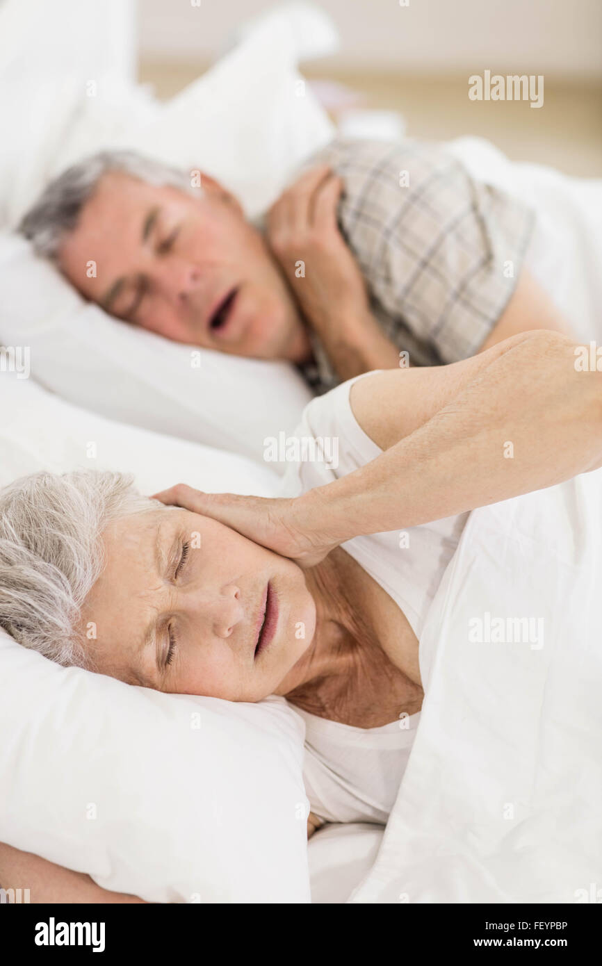 Awake senior woman in bed couvrant ses oreilles Banque D'Images