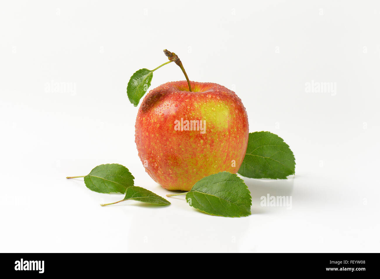 Pomme rouge délavé avec des feuilles sur fond blanc Banque D'Images