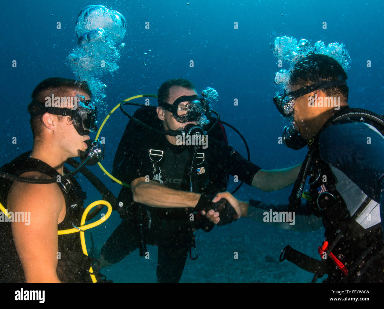 Plongeur de la marine américaine Troy 1ère classe Crowder, affecté à la base navale de Guantanamo Bay, Cuba Dive Locker, montres comme le Capitaine David Culpepper, commandant de la base navale de Guantanamo Bay, félicite ND3 Gordon Brown après son frocking sous-marin au cours d'une cérémonie de corail plongée à l'enquête sur la santé de corail au large de la côte de la Baie de Guantanamo, le 23 novembre 2015. Culpepper permettra de comparer son expérience avec plus de plongées sur récifs facilement accessibles afin d'évaluer les effets possibles de la plongée récréative sur l'écosystème. (U.S. Caméra de combat de la marine photo de Mass Communication Specialist 1re classe Charles E. White/libérés) Banque D'Images