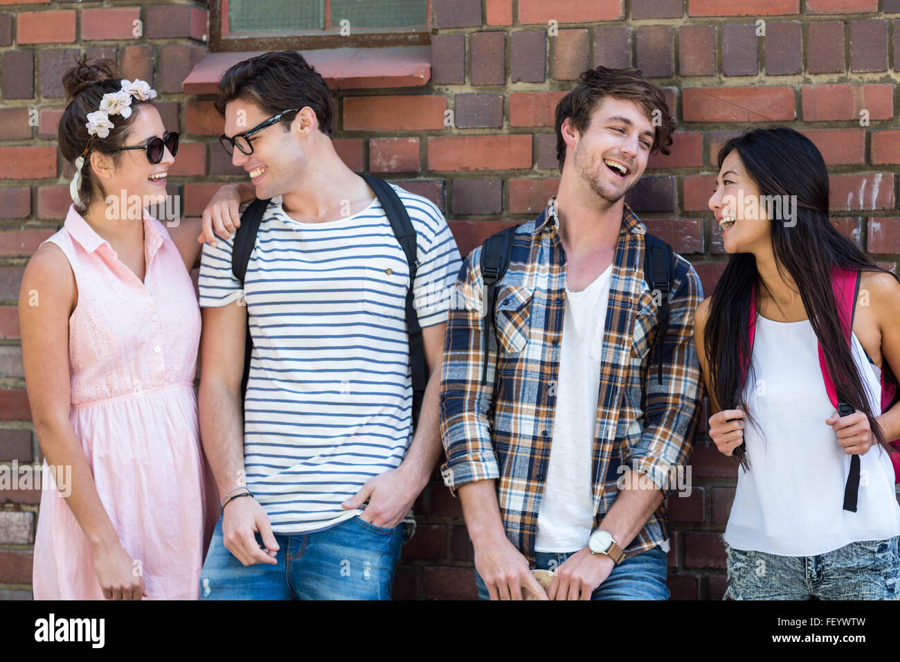 Amis de la hanche leaning against wall Banque D'Images