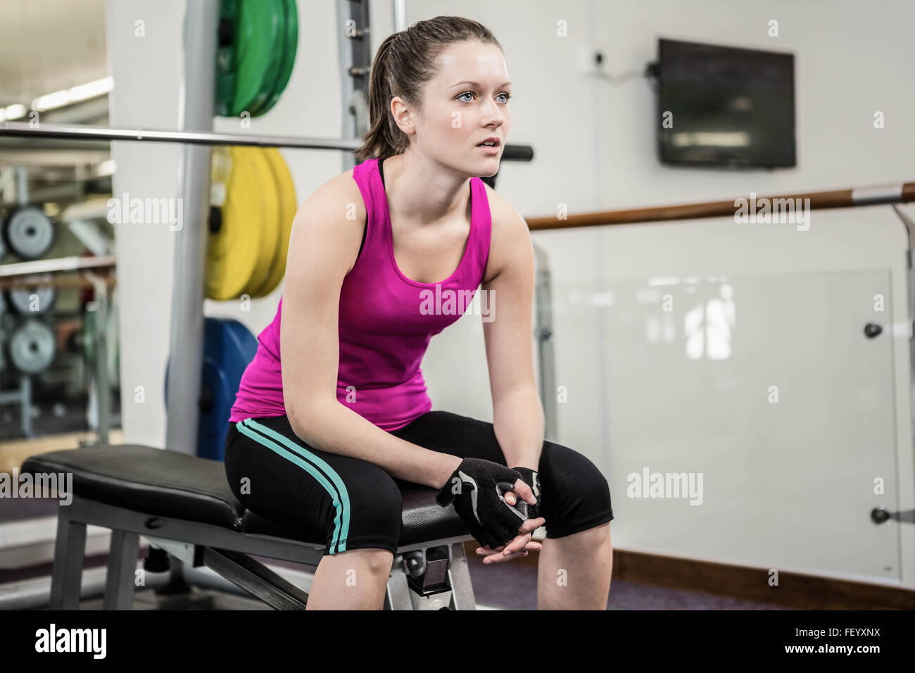 Tired woman sitting on barbell bench Banque D'Images