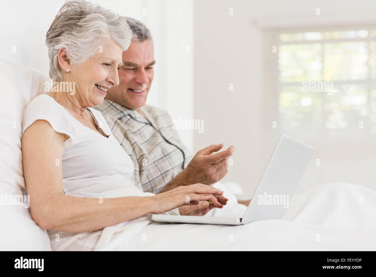 Senior couple using laptop at bed Banque D'Images