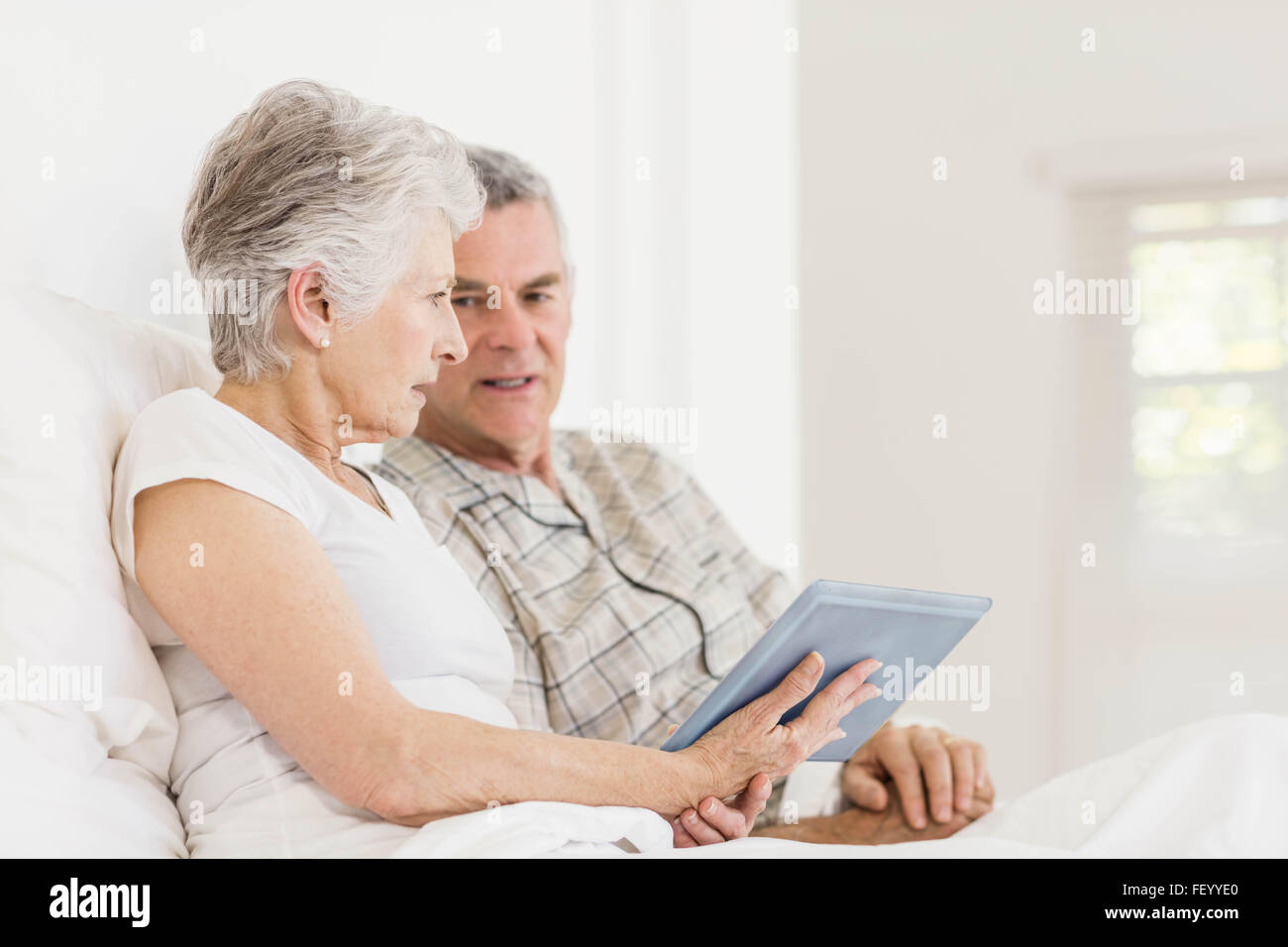 Couple using tablet on bed Banque D'Images