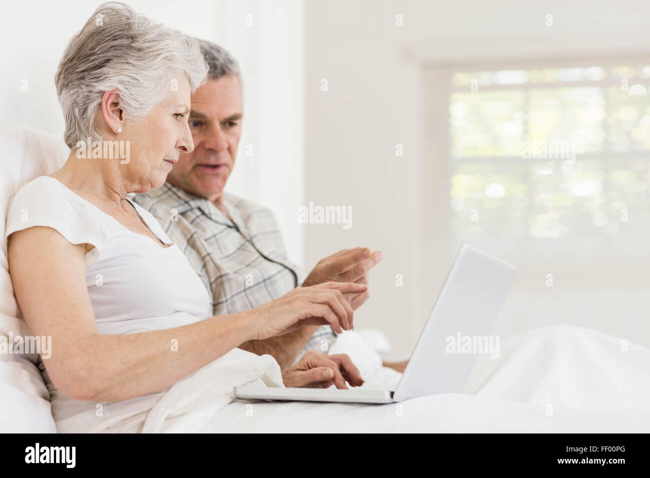 Senior couple using laptop at bed Banque D'Images