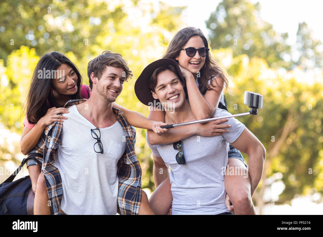 Les hommes de la hanche donnant piggy back pour leurs copines et prendre des selfies Banque D'Images