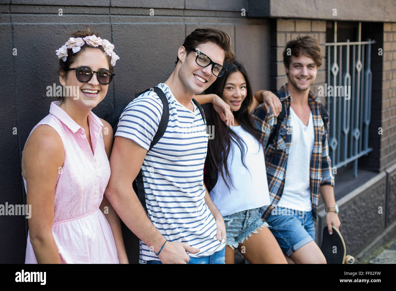Amis de la hanche smiling at the camera et leaning against wall Banque D'Images