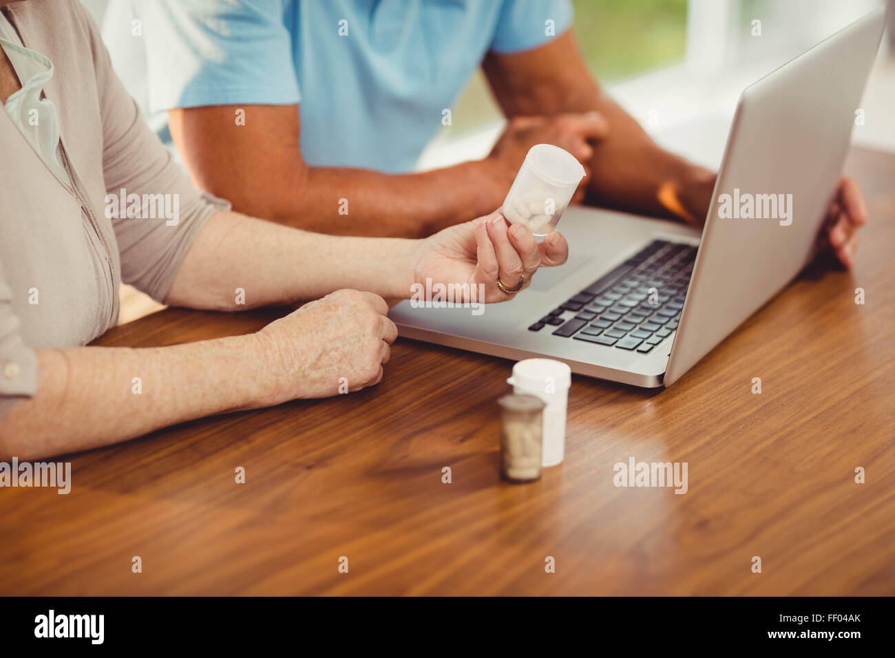 Senior couple using laptop and holding pills Banque D'Images