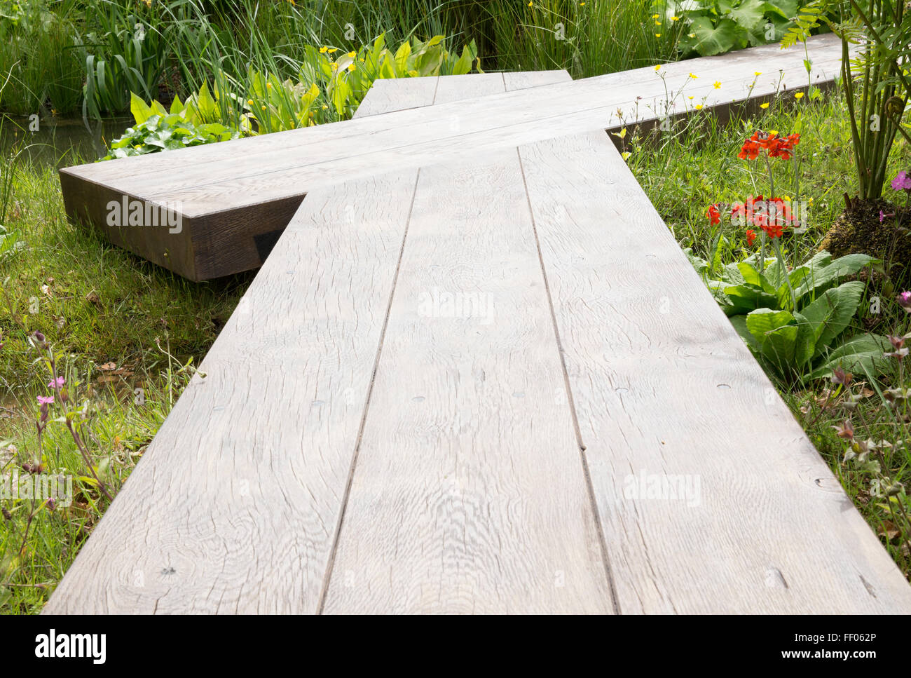 Un jardin animalier avec un sentier de promenade en bois de planche de promenade au-dessus d'un petit ruisseau d'eau caractéristique UK Banque D'Images