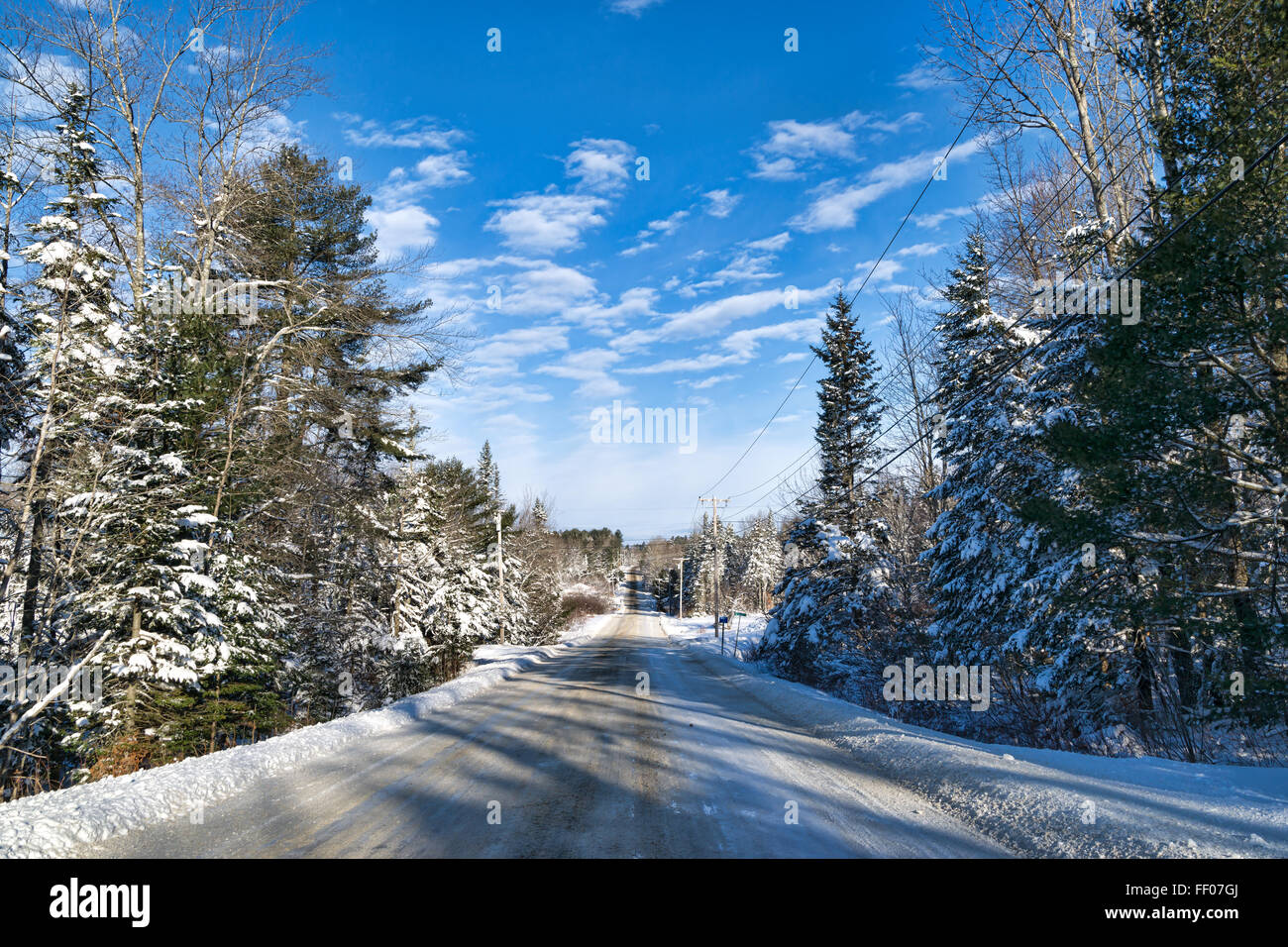 Un chemin rural dans le Maine après une tempête de ciel bleu et nuages filandreux. Banque D'Images