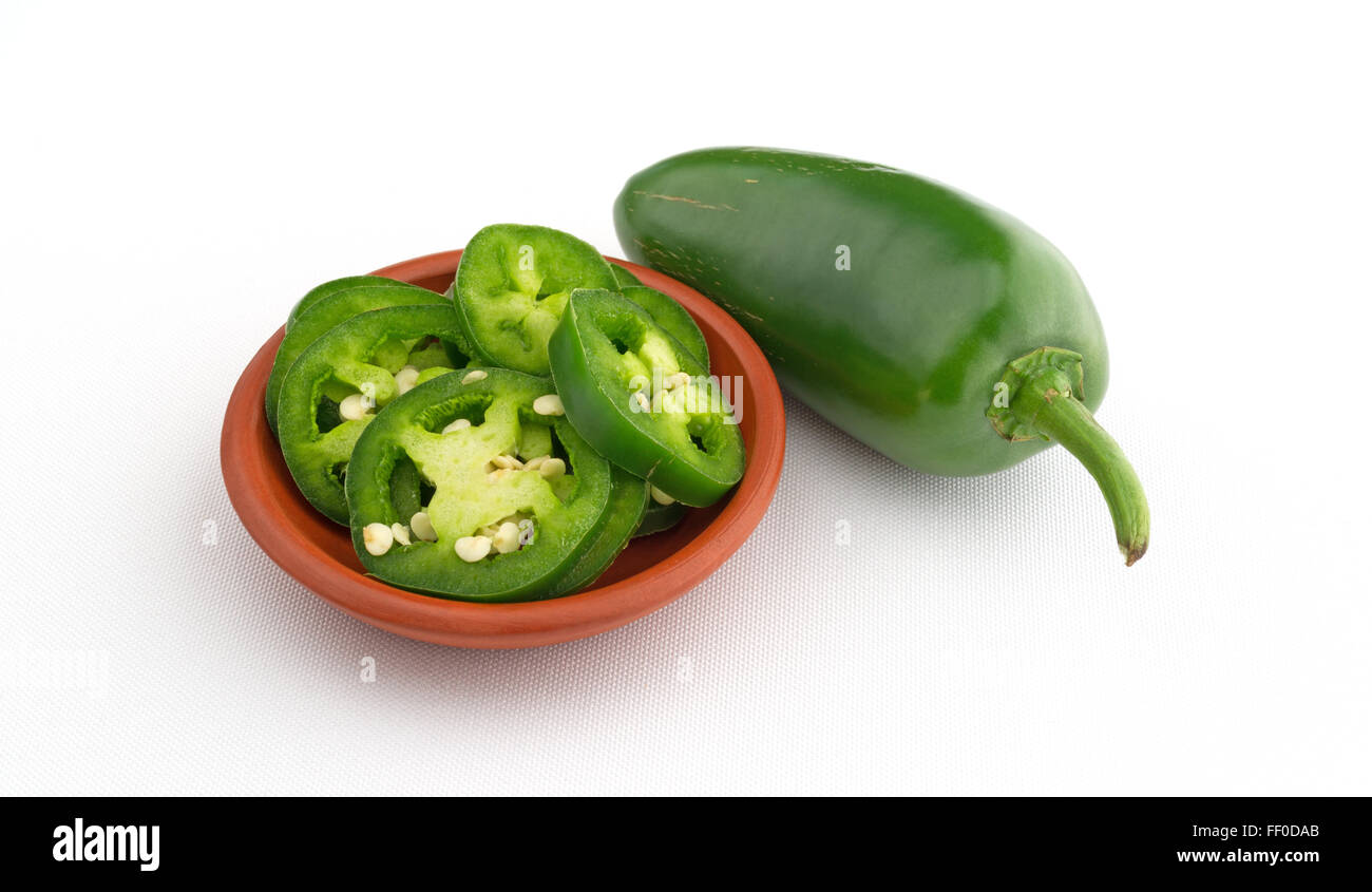 Vue latérale d'un petit bol de tranches de piment jalapeño poivre ainsi qu'un grand ensemble à la côte sur une nappe blanche Banque D'Images