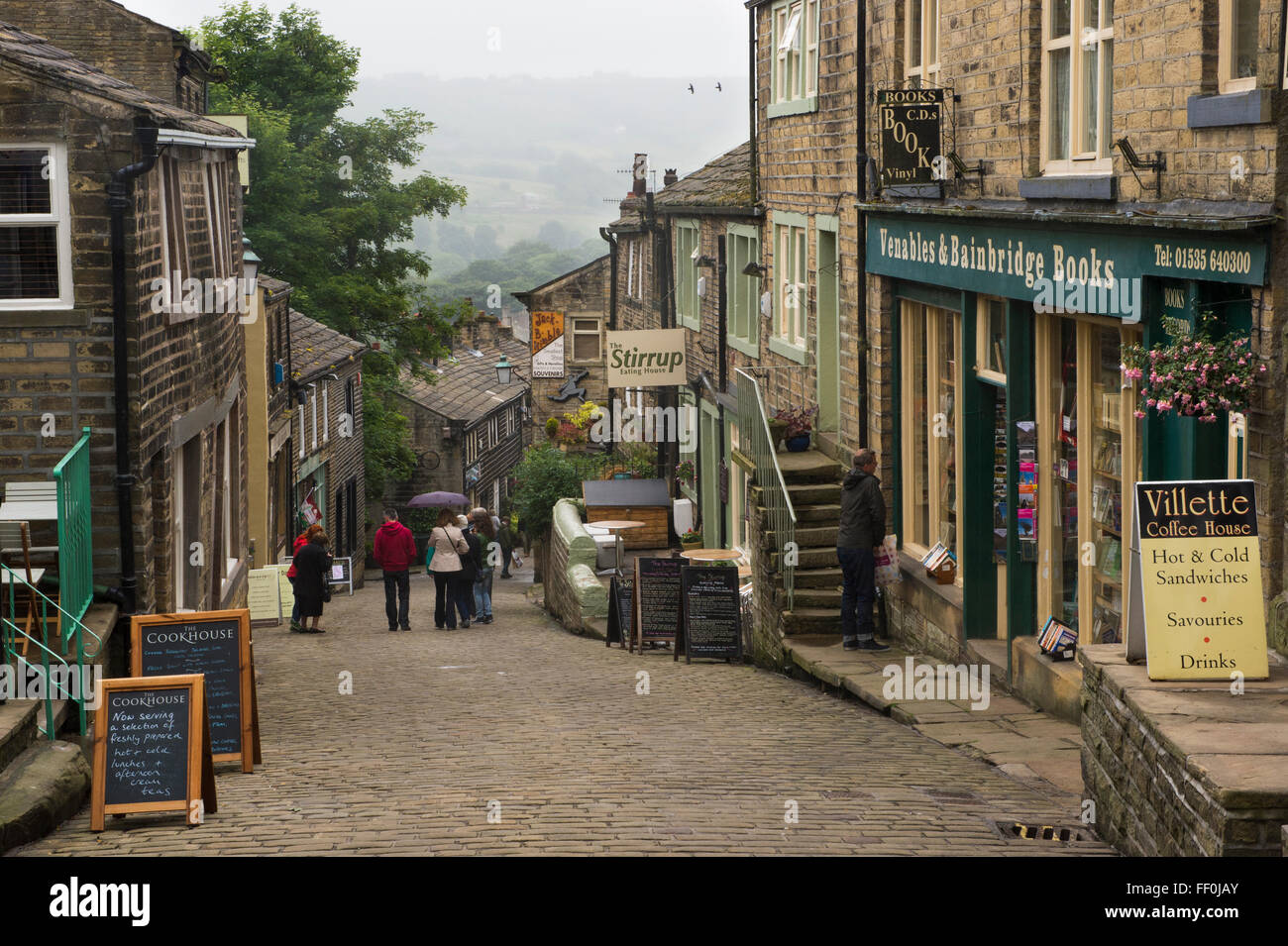 Les gens marcher dans la rue Main raide, Haworth, West Yorkshire, Angleterre - pittoresque, ruelles pavées, bordées de boutiques, populaire auprès des visiteurs Bronte Country ! Banque D'Images