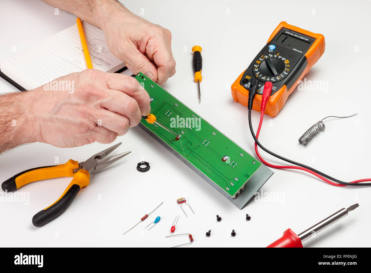 Ingénieur en électronique à son établi à l'aide d'un tournevis sur une carte à circuits imprimés Banque D'Images