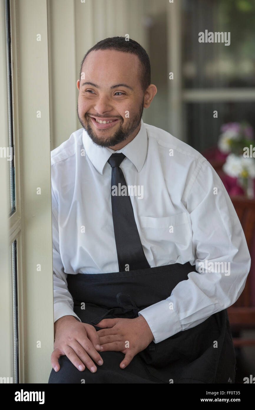 Mixed Race server avec syndrome de Down smiling in restaurant Banque D'Images