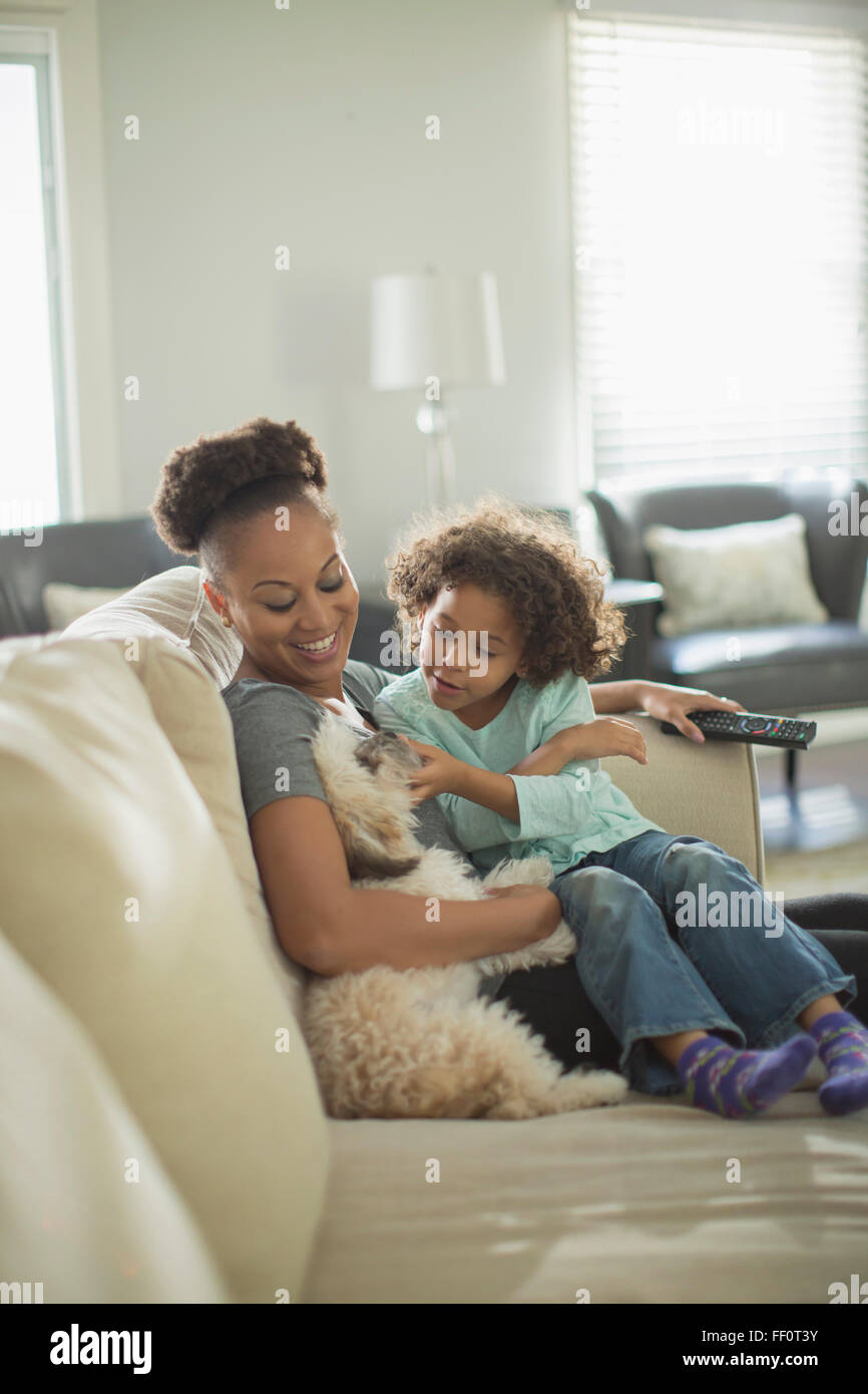 Mère et fille petting dog on sofa Banque D'Images