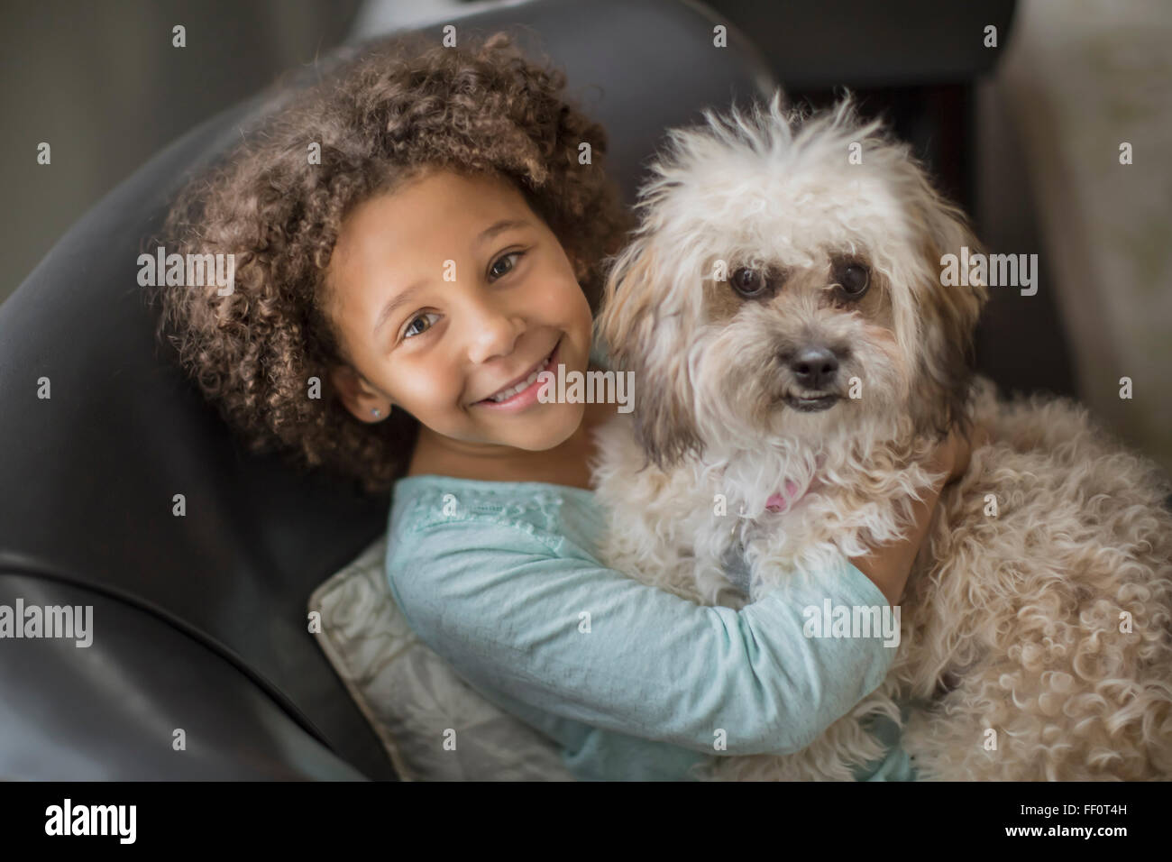 Mixed Race girl petting dog on sofa Banque D'Images