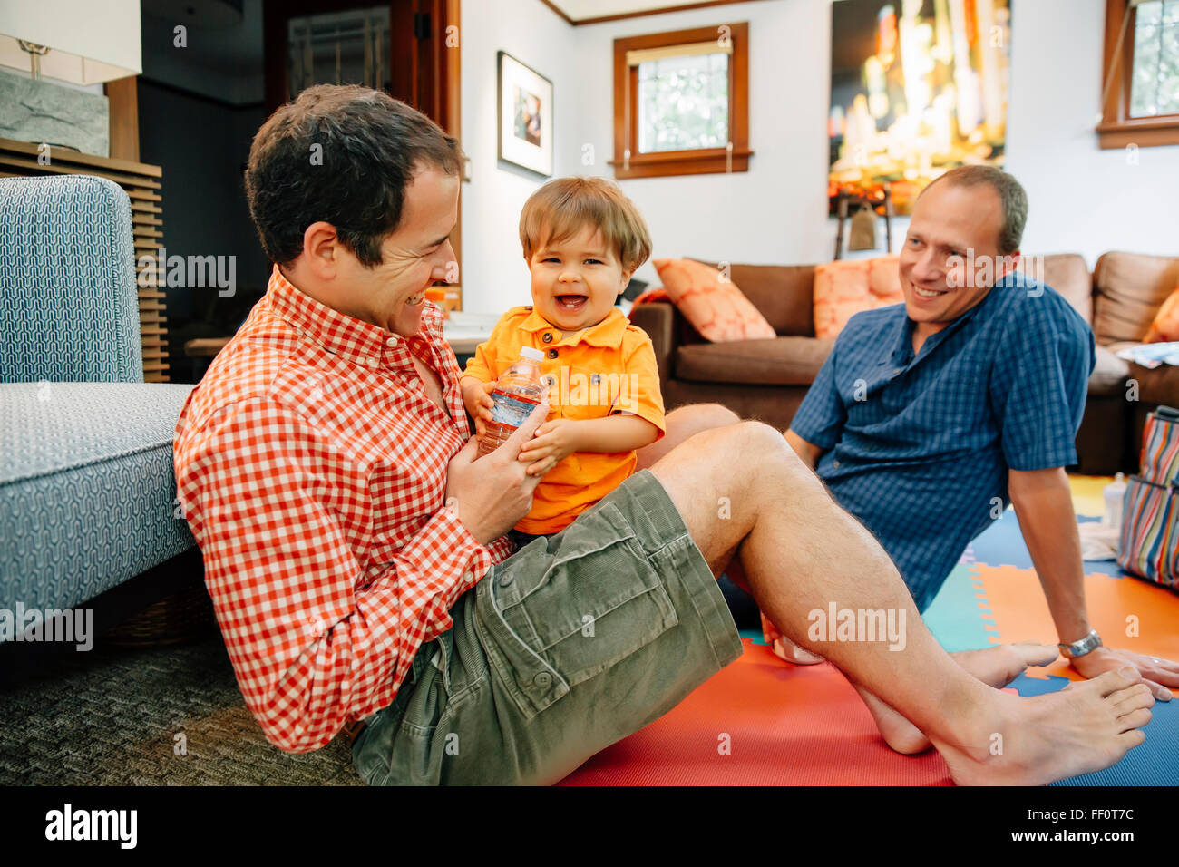 Les pères gays jouer avec bébé dans la salle de séjour Banque D'Images
