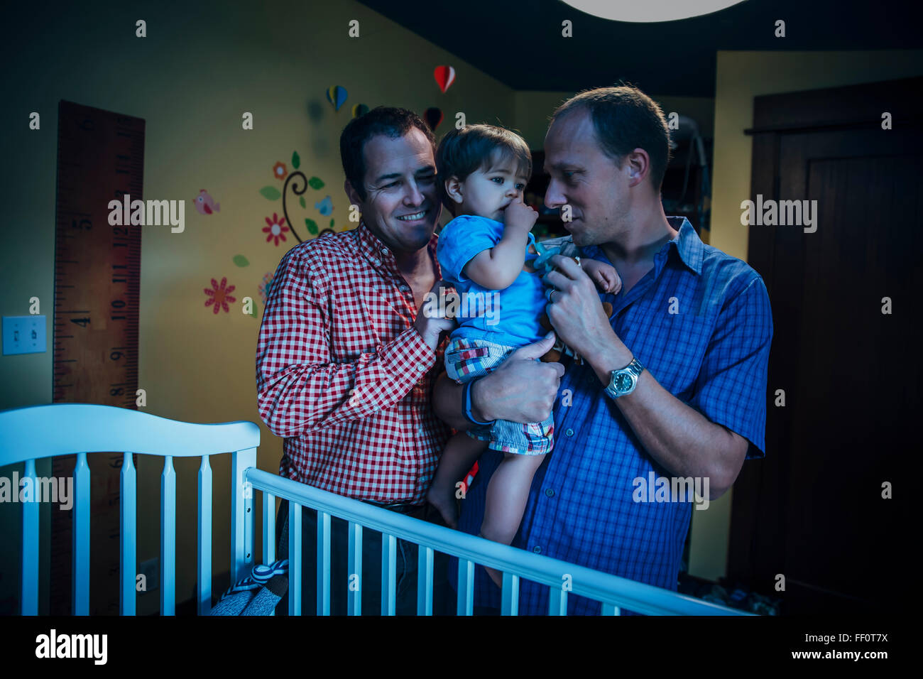 Les pères gays holding baby son in nursery Banque D'Images