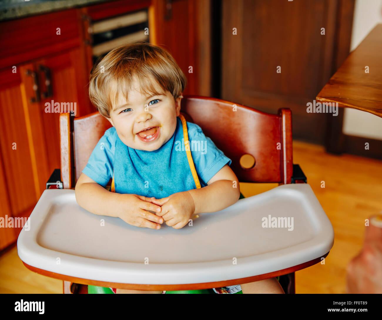 Bébé garçon rire dans une chaise haute Banque D'Images
