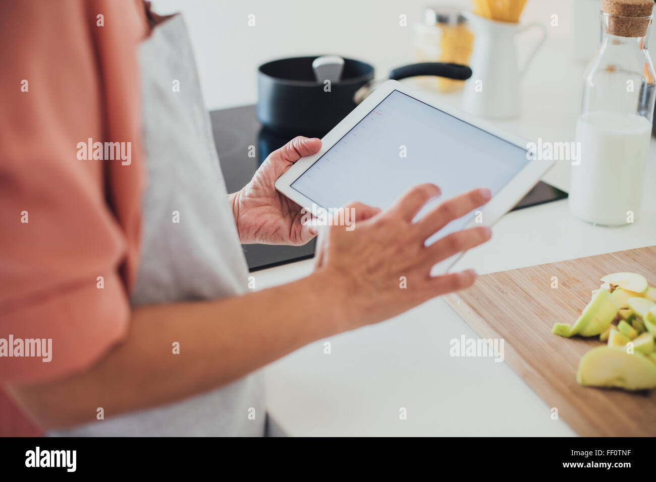Older Caucasian woman using digital tablet in kitchen Banque D'Images