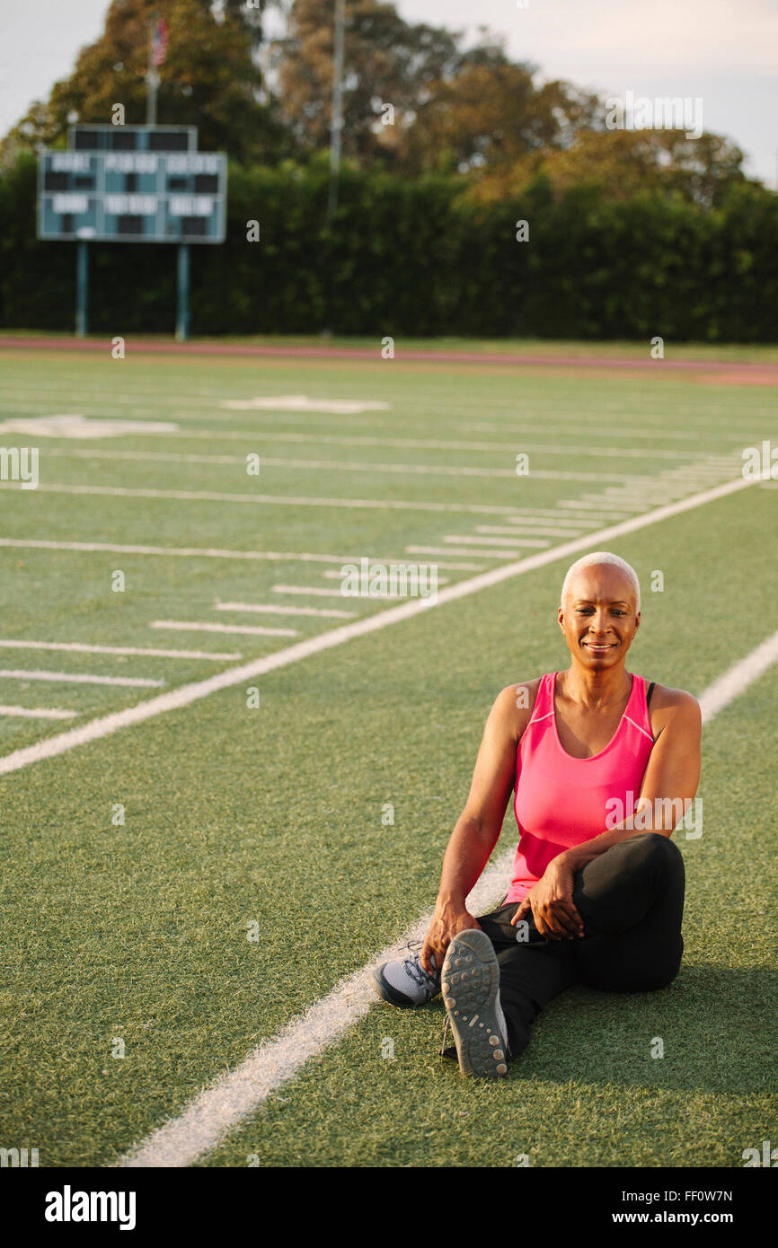 Woman stretching sur terrain de football Banque D'Images
