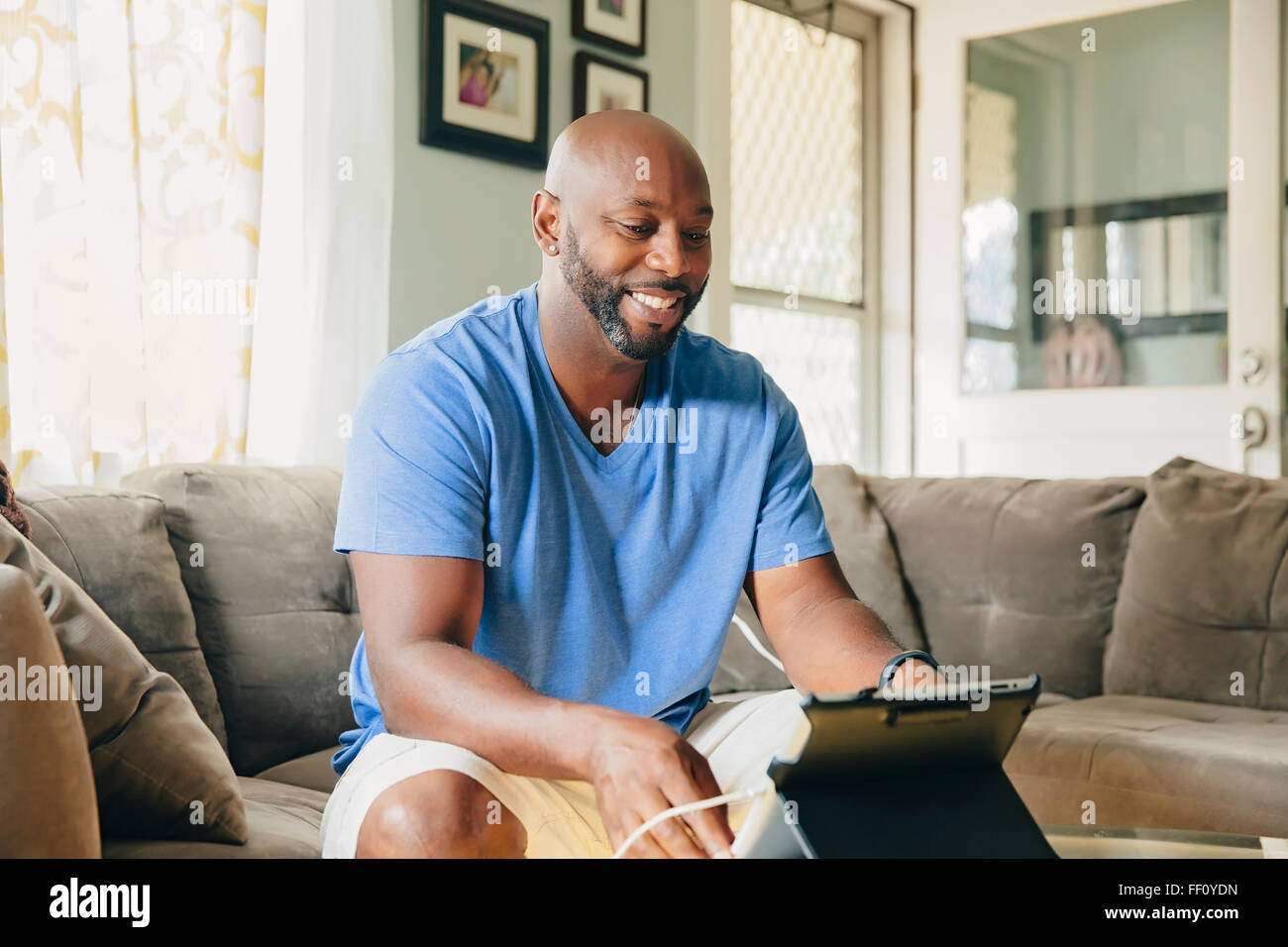 Black man using digital tablet in living room Banque D'Images