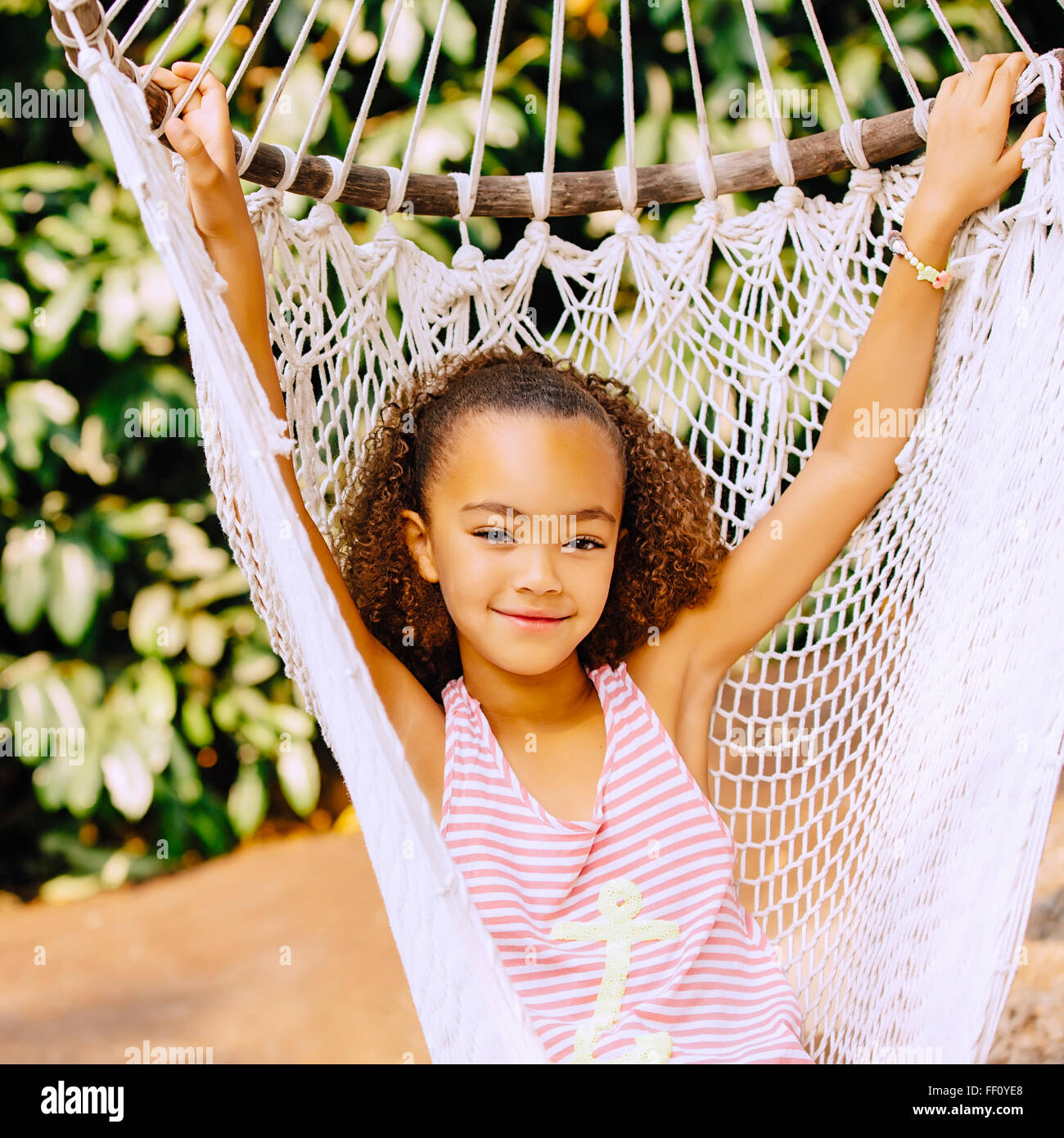 Mixed Race girl sitting in hammock Banque D'Images