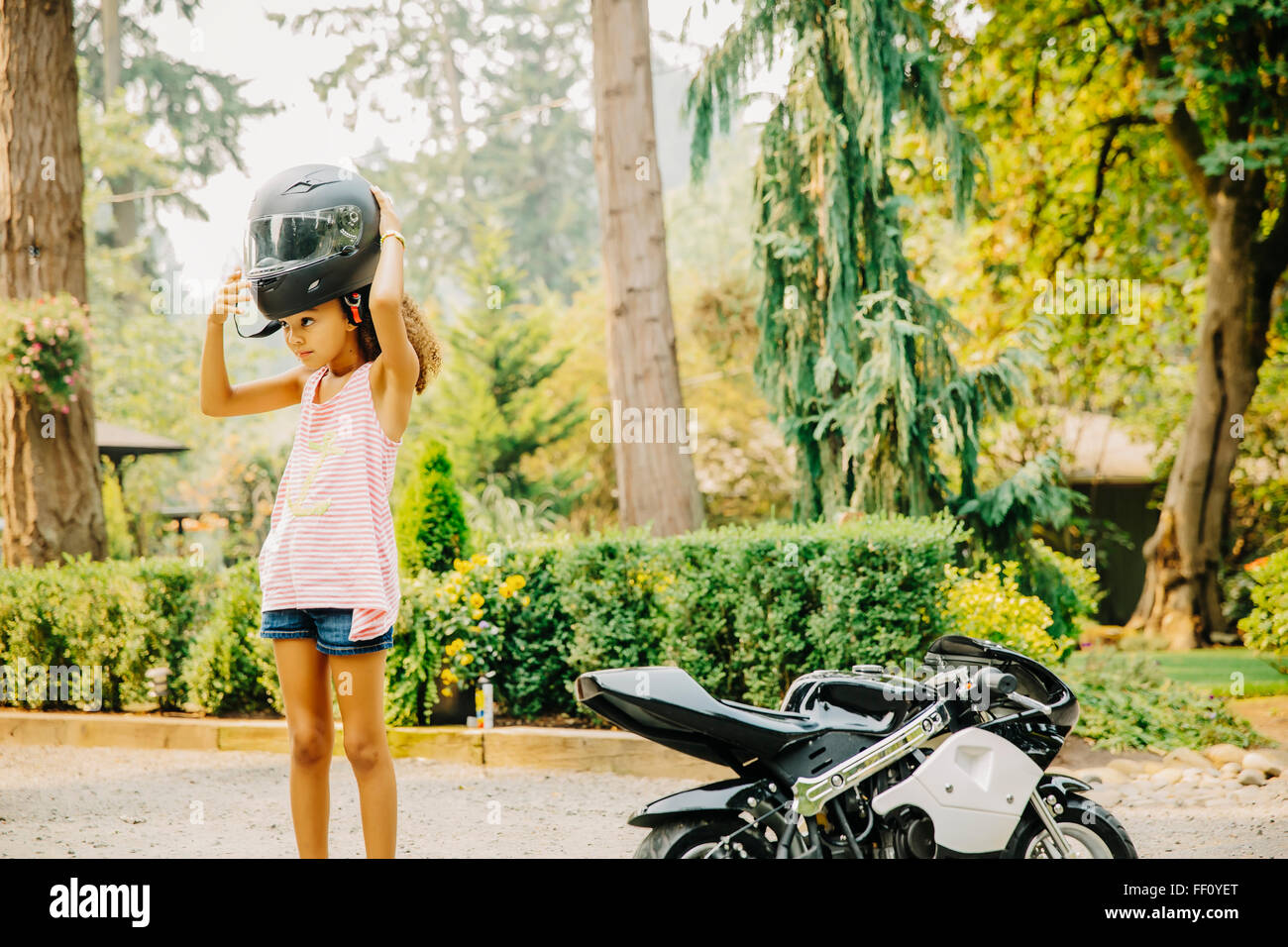 Mixed Race girl putting on helmet Banque D'Images