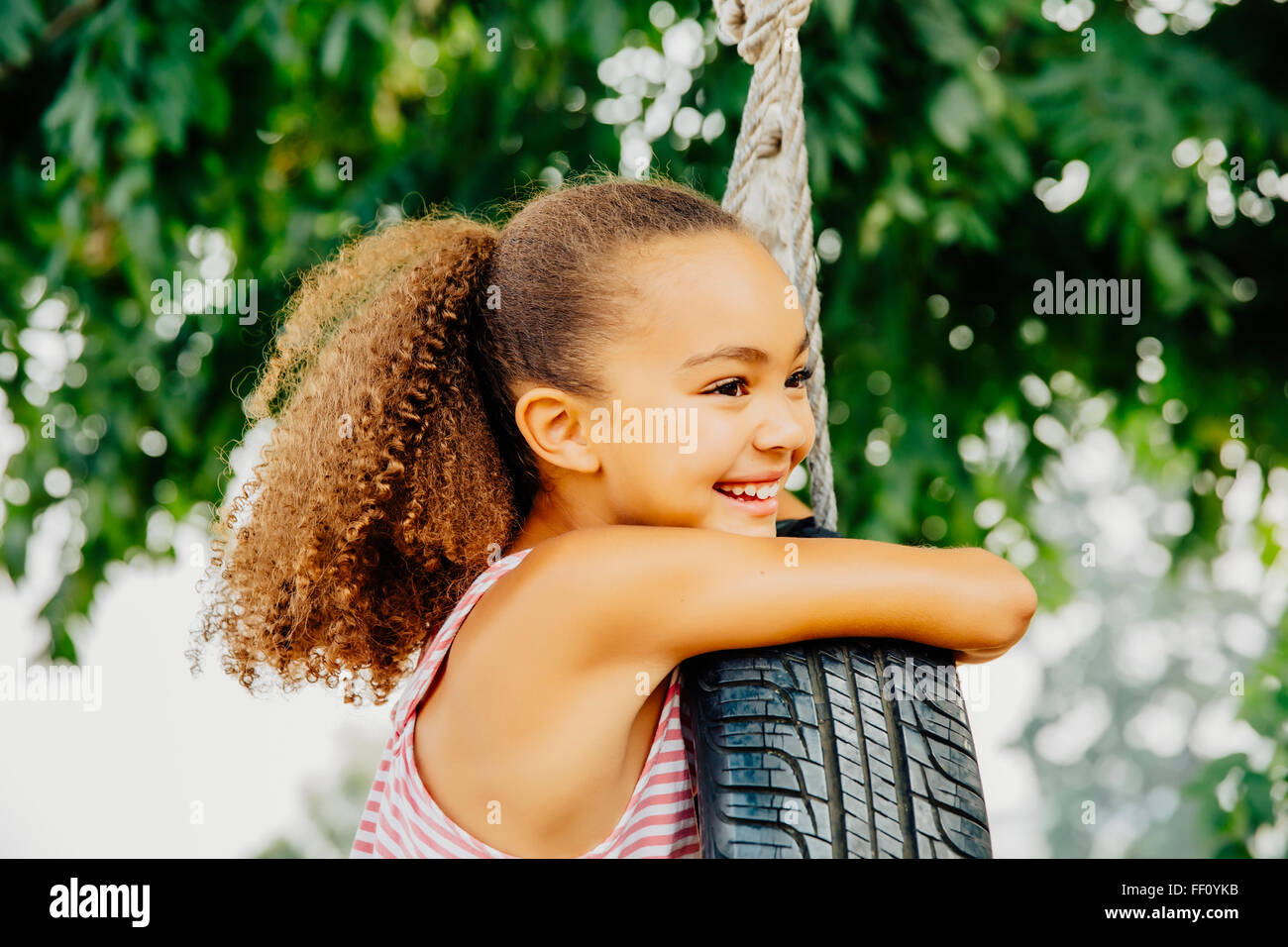 Mixed Race girl smiling in balançoire pneu Banque D'Images