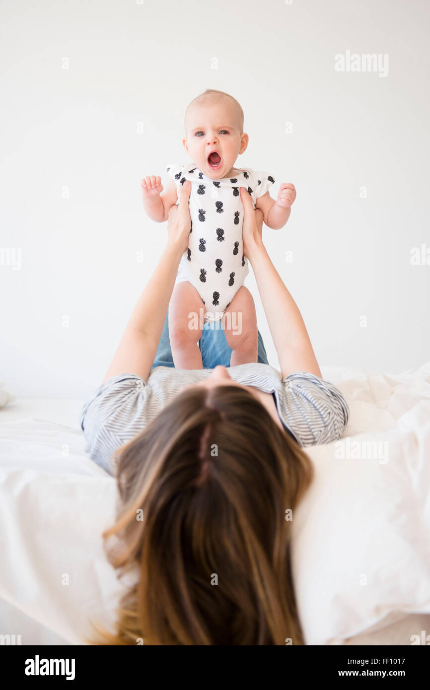 Caucasian mother holding baby daughter on bed Banque D'Images