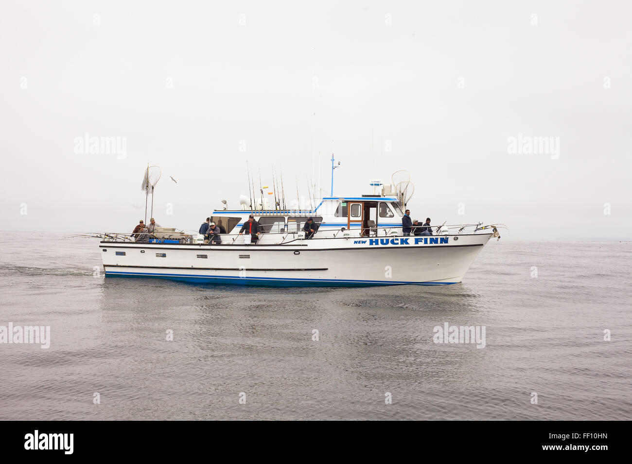 Un groupe de pêcheurs la pêche au saumon sur un bateau sur l'eau calme d'un après-midi de brouillard gris. Banque D'Images