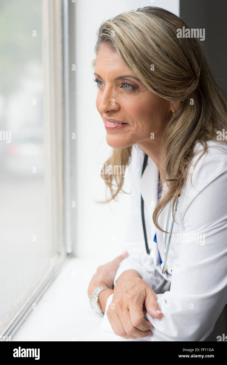 Caucasian doctor looking out window Banque D'Images